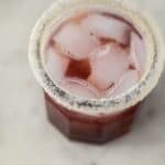 cherry margarita in sugar rimmed glass with ice on marble