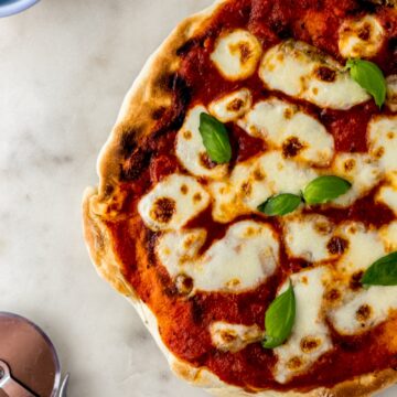 overhead view margherita pizza next to pizza cutter