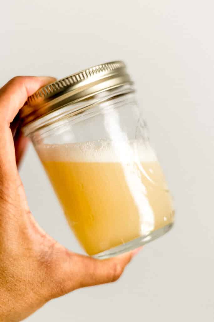 hand holding jar with lid on it with margarita mixture in it.