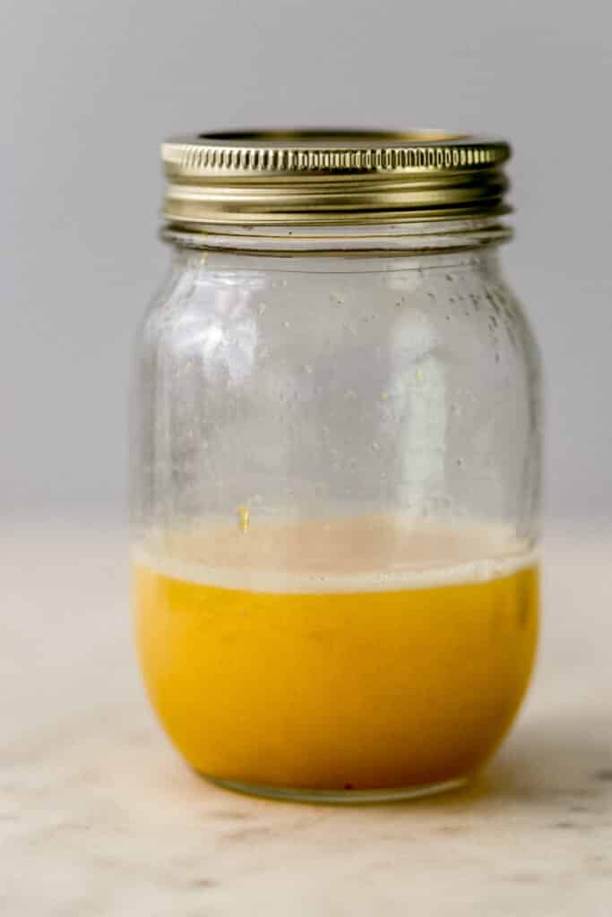 side view ingredients for peach margarita in jar with lid on it. 