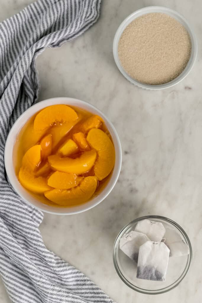 ingredients for peach tea in small bowls with cloth napkin 