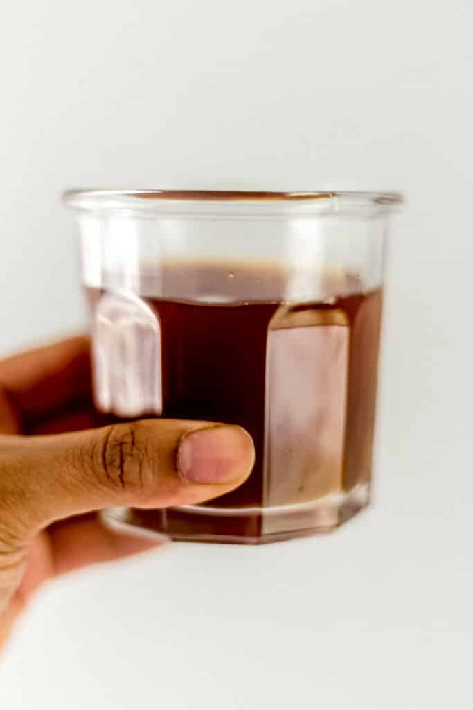 hand holding glass with peach tea in it. 