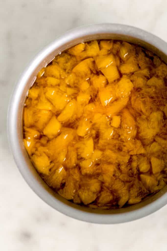 peaches mashed in simple syrup in sauce pan for peach tea recipe