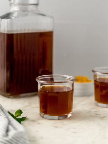 pitcher and two glasses with peach tea in them.