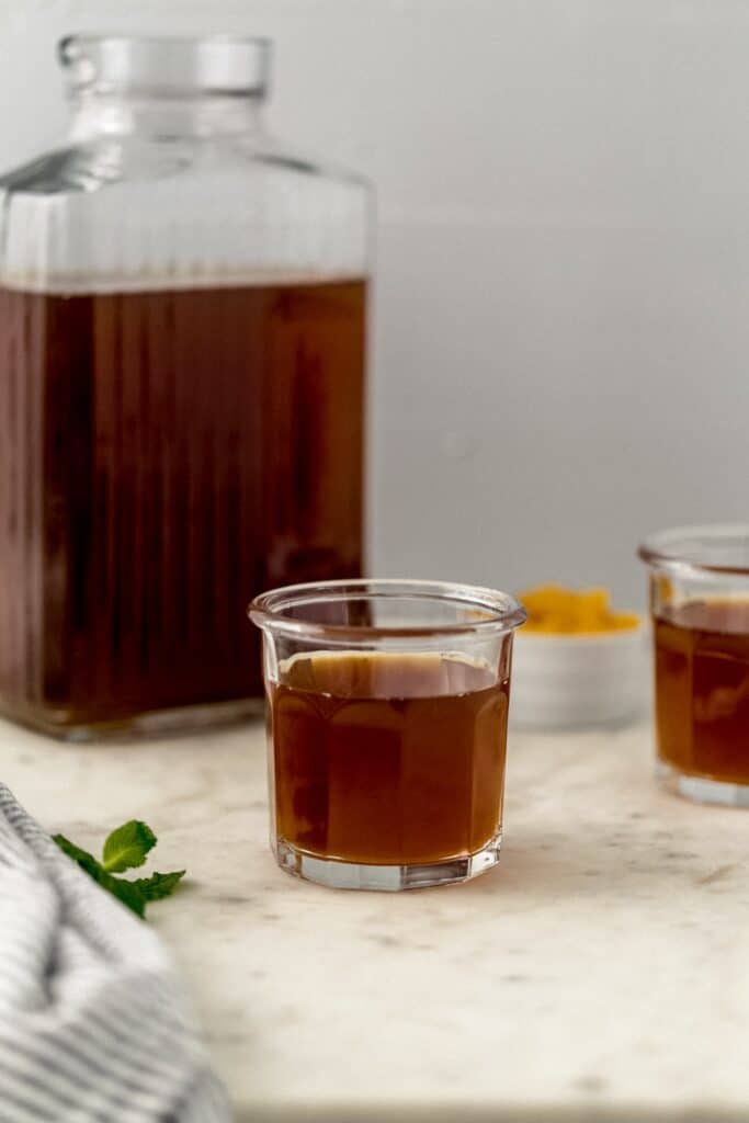 pitcher and two glasses with peach tea in them.