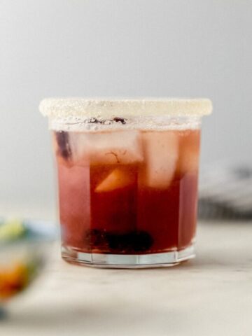 close up side view cherry margarita in sugar rimmed glass with ice