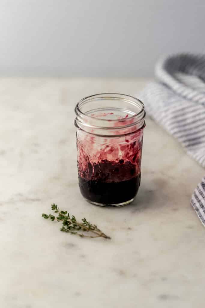 fresh blackberries and thyme muddled in glass jar 