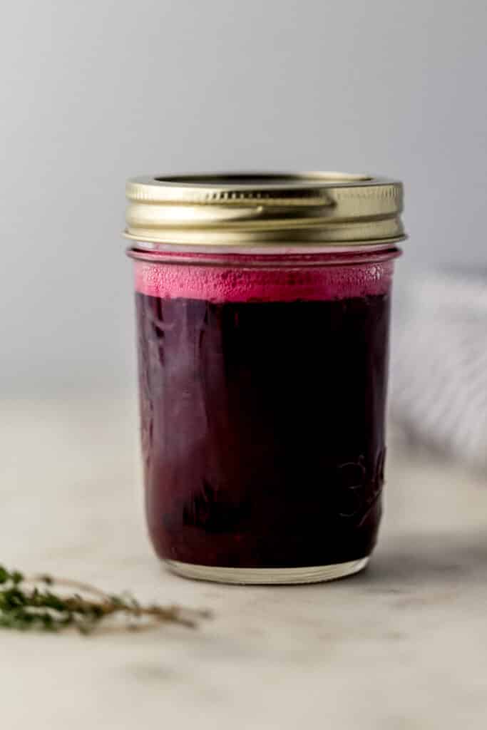 glass jar with lid on it with blackberry margarita in it. 