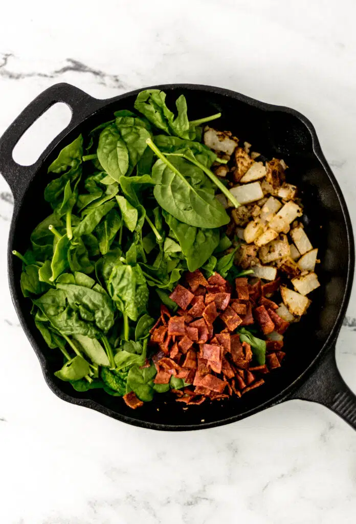 spinach and bacon with potato and onion in cast iron skillet