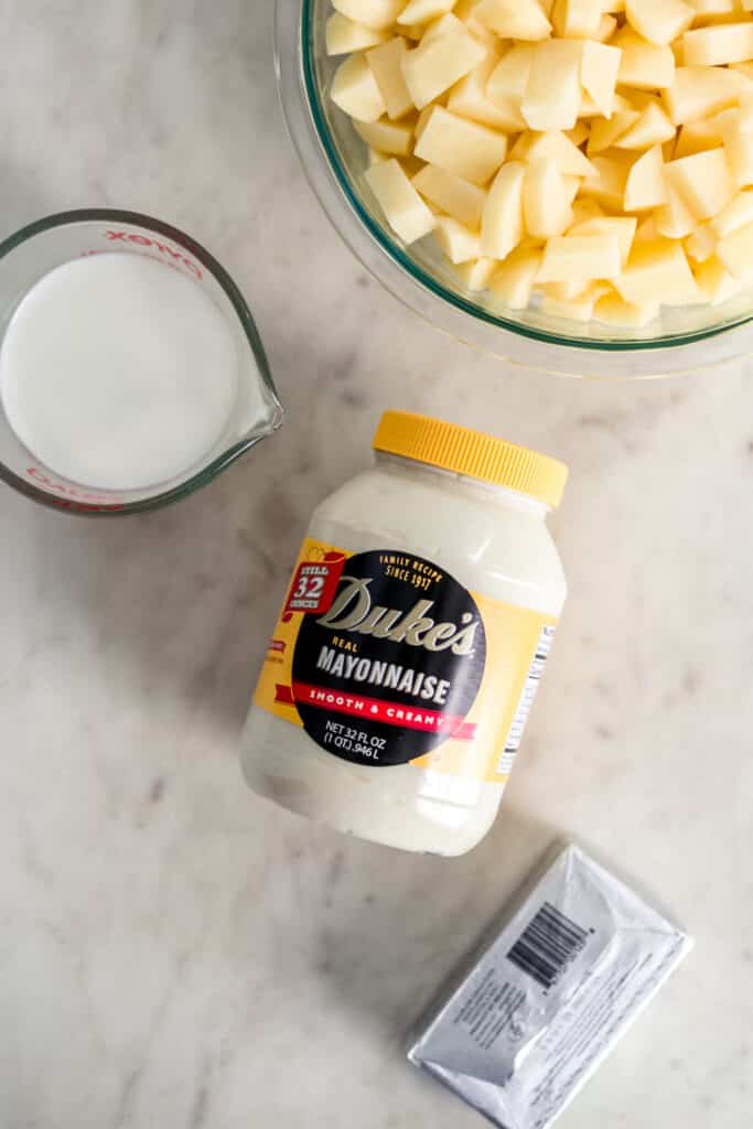 ingredients to make creamy mashed potatoes in separate containers. 
