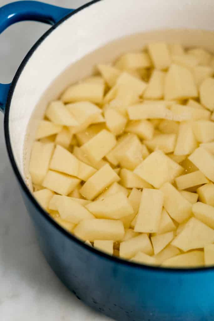 large pot with cut up potatoes in water in it. 