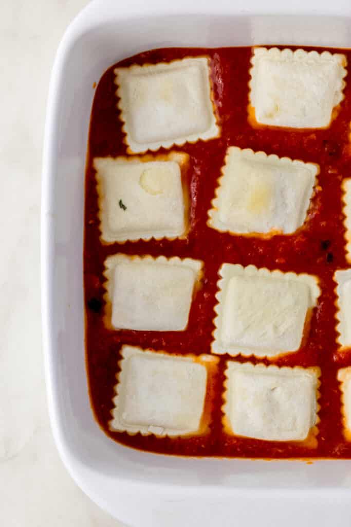 frozen ravioli and sauce in square white baking dish 