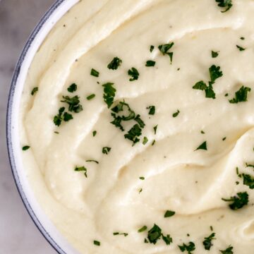 bowl of creamy mashed potatoes topped with fresh parsley