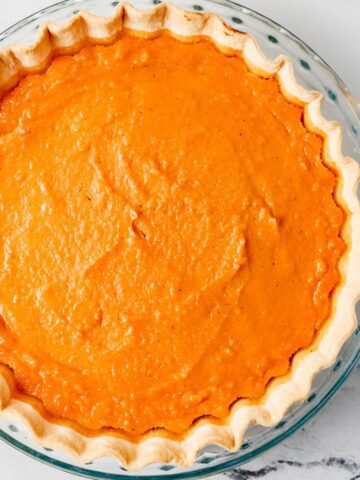 Overhead view of whole baked pie in dish on marble surface.