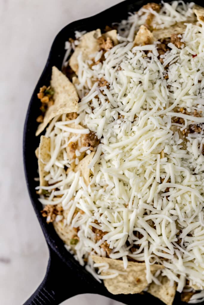 tortilla chips, ground pork, and mozzarella cheese in cast iron skillet