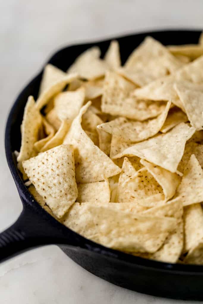 close up side view ingredients for pork nachos in cast iron skillet