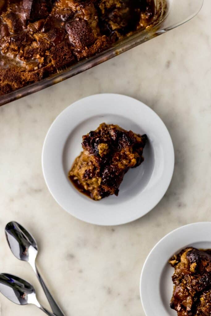 peach bread pudding in baking dish and on two white plates with spoons