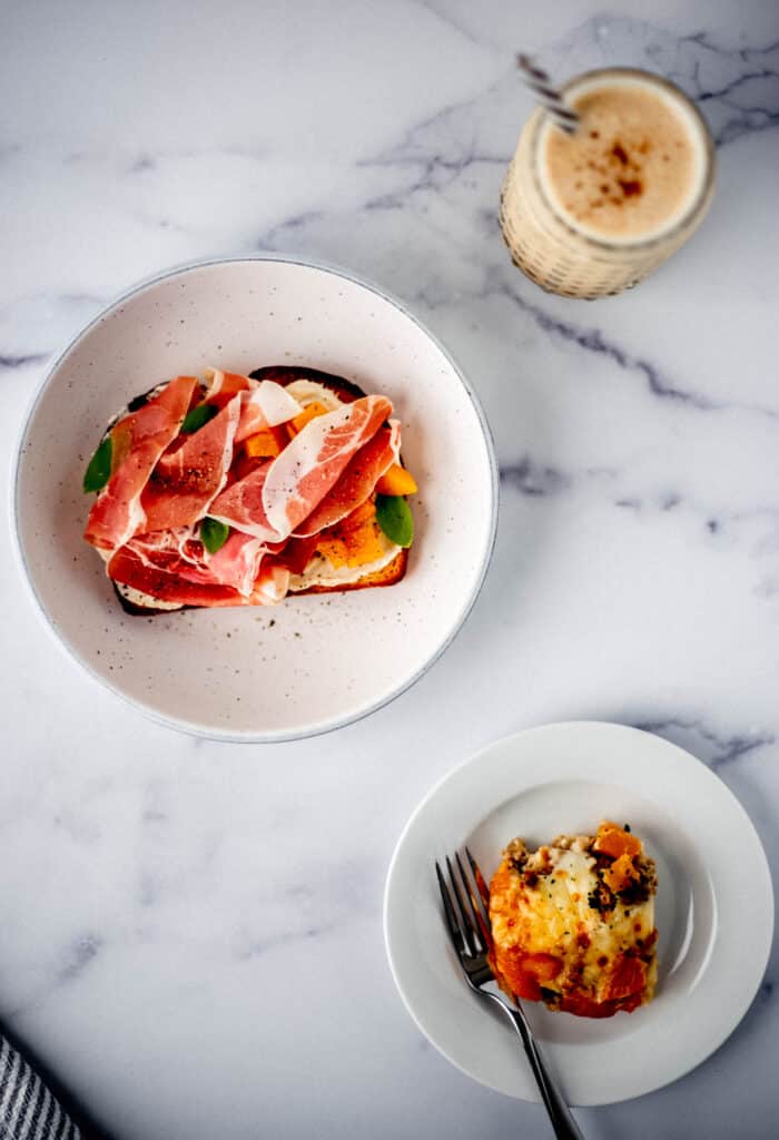 overhead view of smoothie, toast, and plate with strata on a marble surface. 