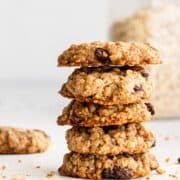Close up side view of stacked cookies by jar of oats.