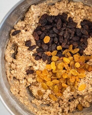 Raisins added to other cookie ingredients in a stand mixer bowl.