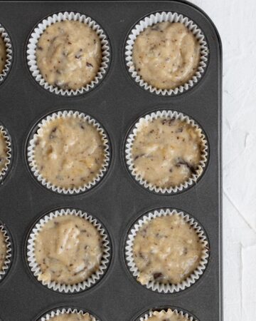 Muffin batter added to muffin pan with liners.