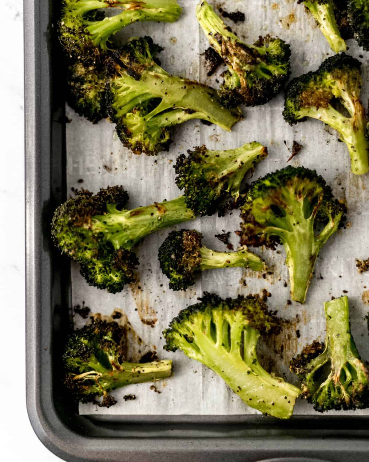 Overhead view of finished broccoli on parchment lined sheet pan. 