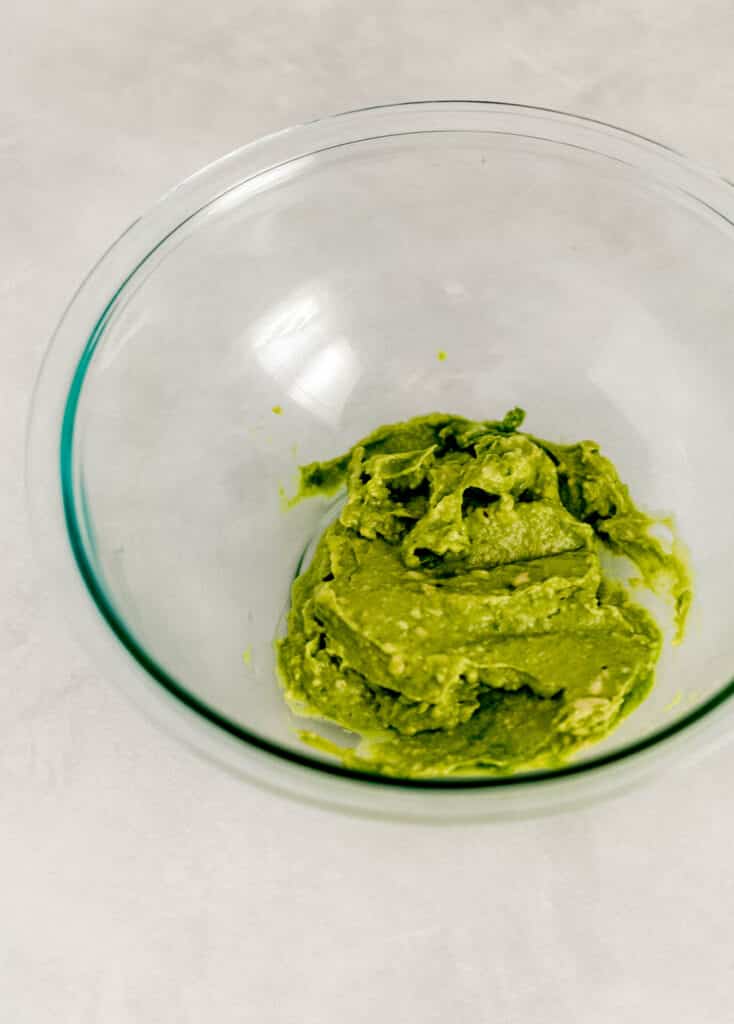 mashed avocado in glass mixing bowl. 