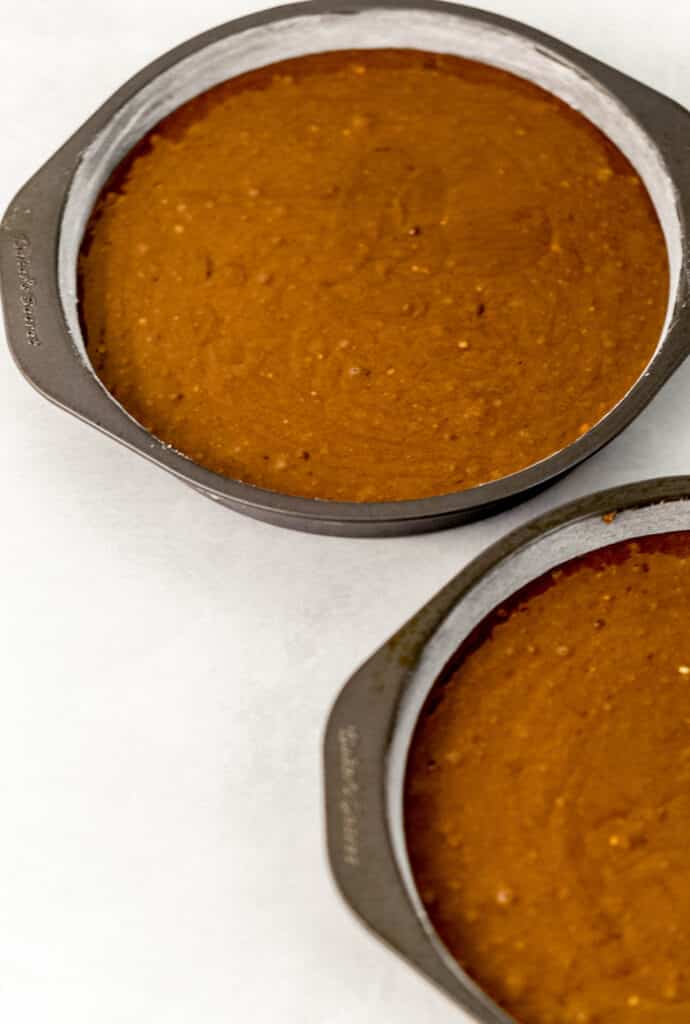 chocolate cake mixture poured into two round cake pans. 