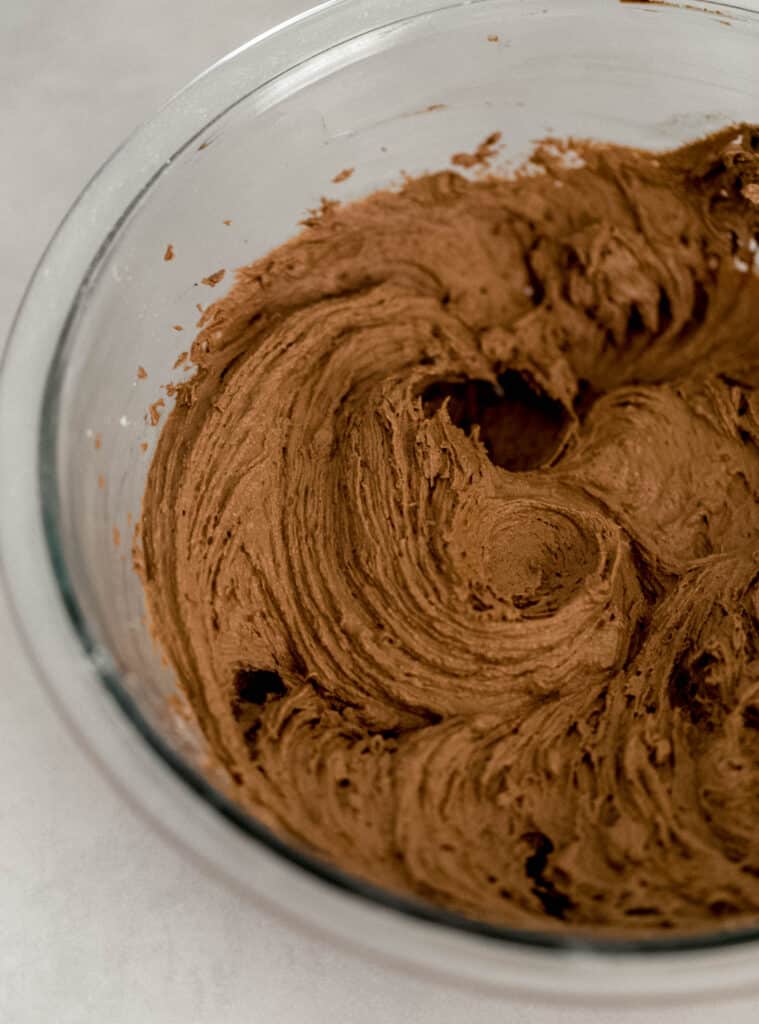 chocolate frosting for cake in glass mixing bowl. 