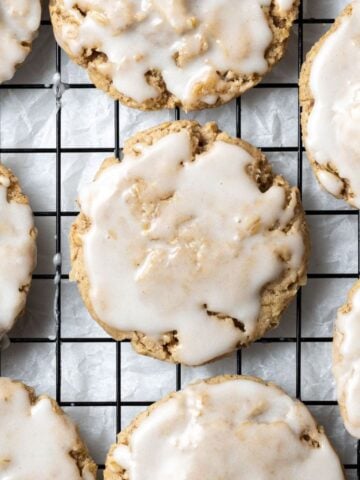Overhead view of iced cookies on baking rack over parchment paper.