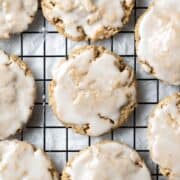Overhead view of iced cookies on baking rack over parchment paper.