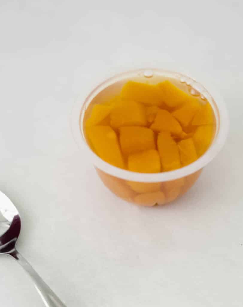 small container of died cling peaches with a spoon 