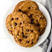 Overhead view of large white plate of cookies by cloth napkin.