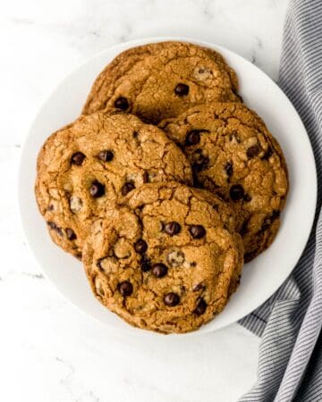 Overhead view of large white plate of cookies by cloth napkin.