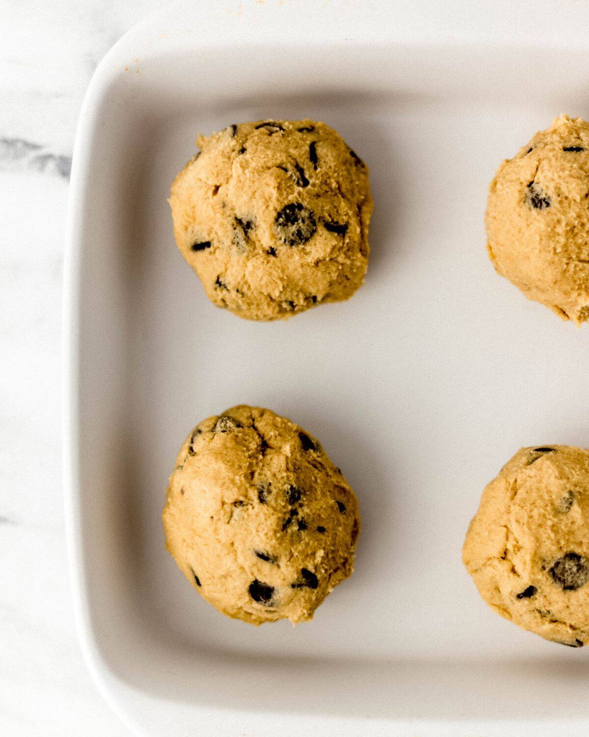 Cookie dough balls in square white baking dish.