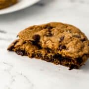 Close up side view of cookie broke in half on marble surface.