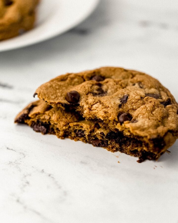 Close up side view of single cookie broke in half on marble surface.