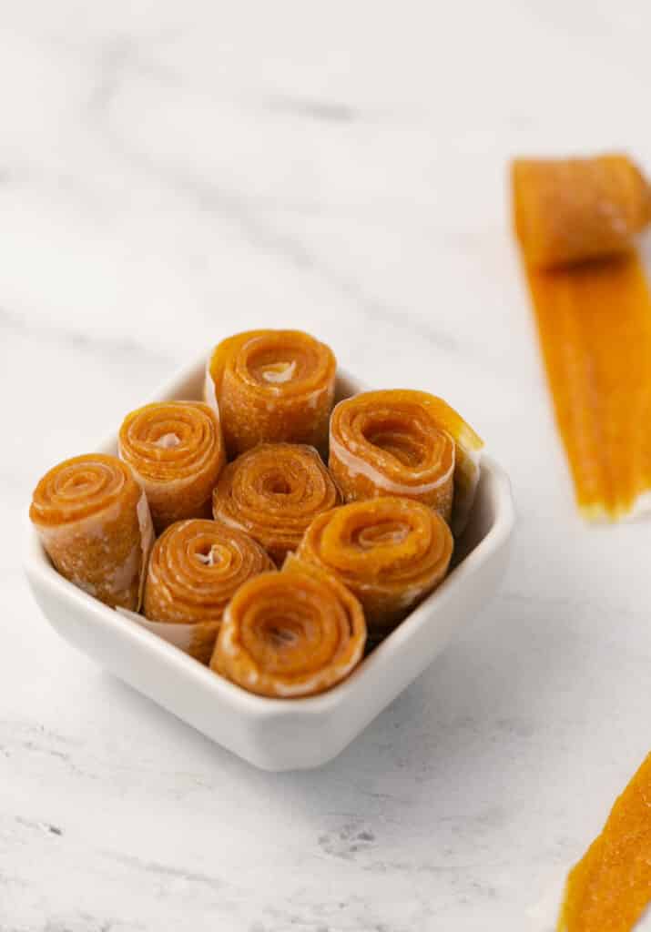 close up side view fruit leather in small square white bowl