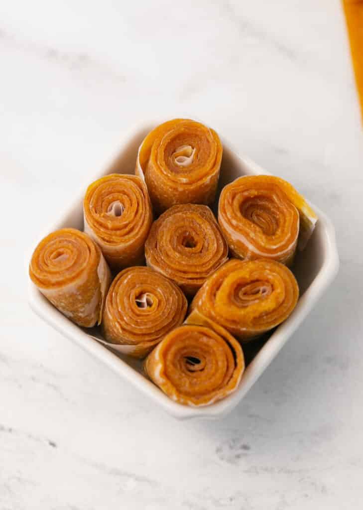 fruit leather rolled up in separate pieces in square white bowl