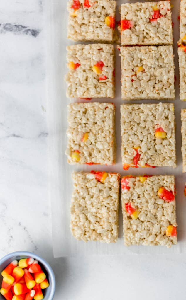 candy corn rice krispie treats cut into small squares on parchment paper