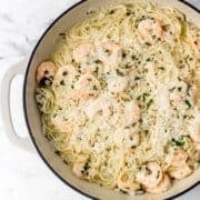 Finished shrimp scampi in large white braiser pan.