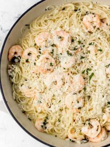 Finished shrimp scampi in large white braiser pan.
