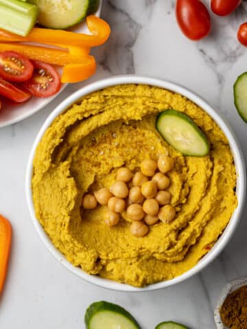 curry hummus in white bowl with vegetables