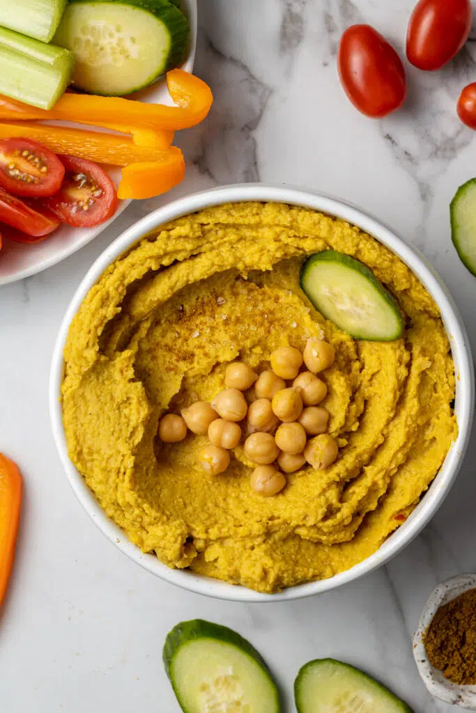 curry hummus in white bowl with vegetables 