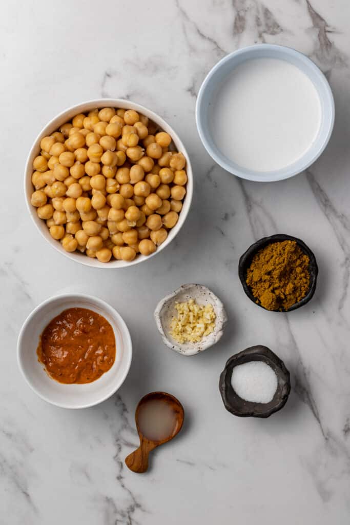 ingredients needed to make hummus on marble surface in separate bowls