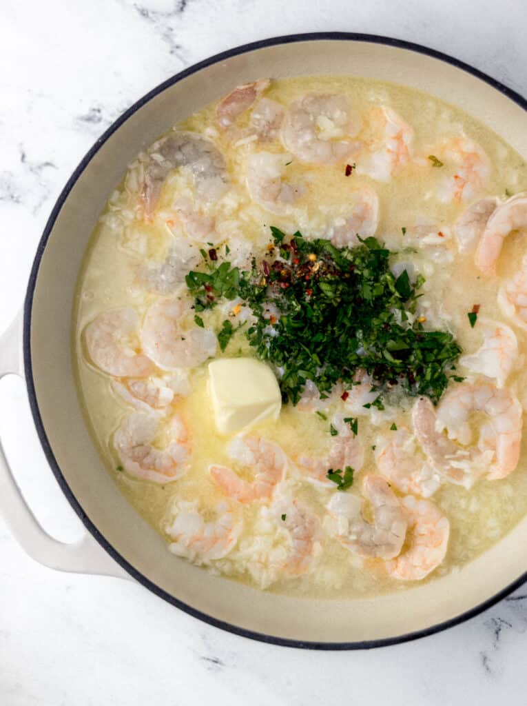 overhead view large cast iron skillet with shrimp scampi sauce. 