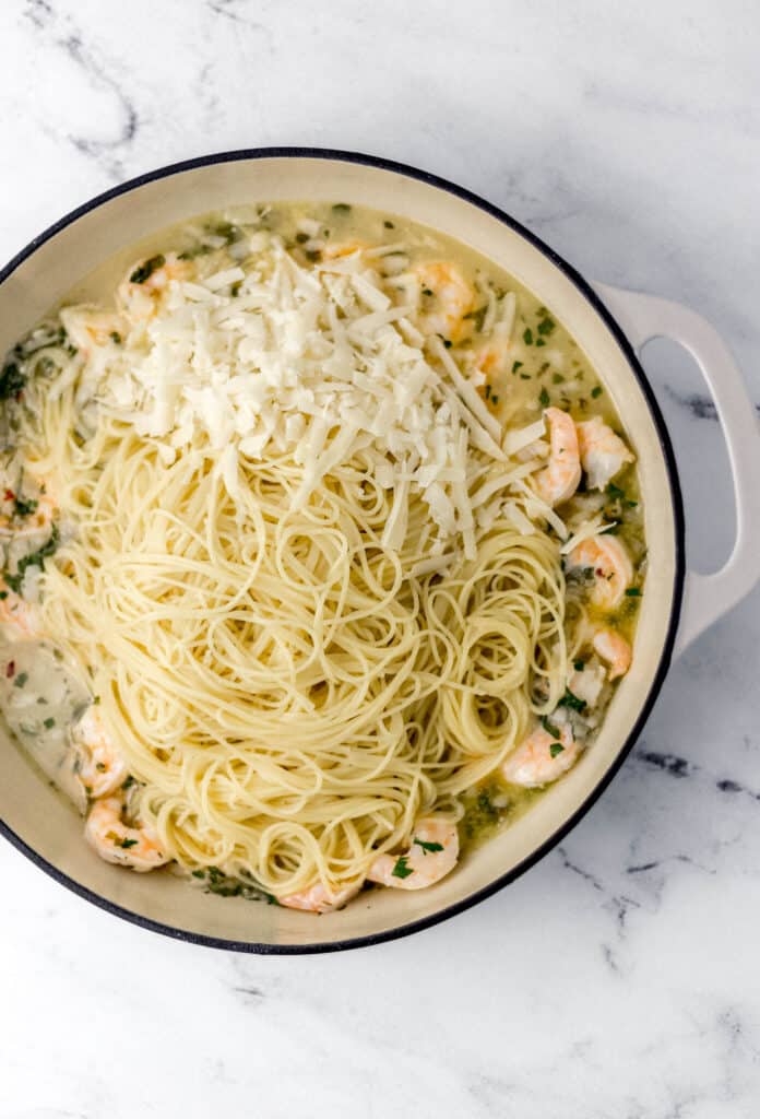 shrimp scampi sauce in pot topped with pasta and cheese