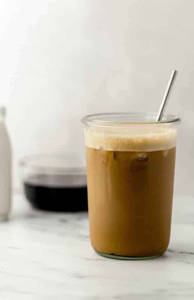 close up side view iced espresso in glass with metal straw. 