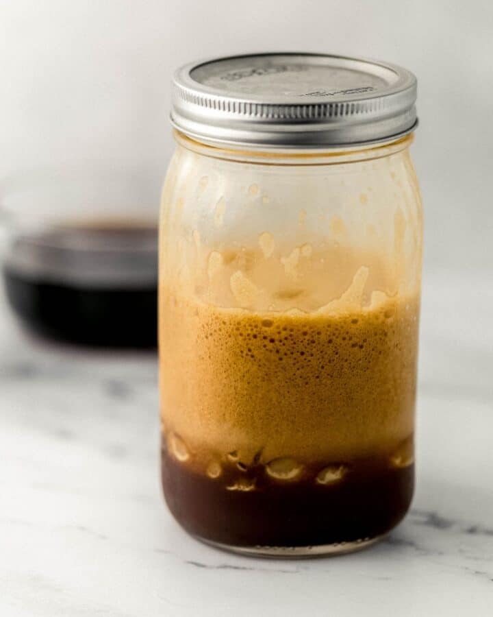 Side view of shaken espresso and ice in glass jar with lid. 