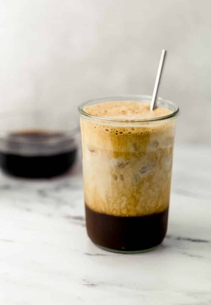 shaken espresso in glass topped with oat milk 